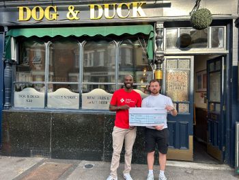 James stood outside The Dog and Duck pub with a cheque for London's Air Ambulance Charity