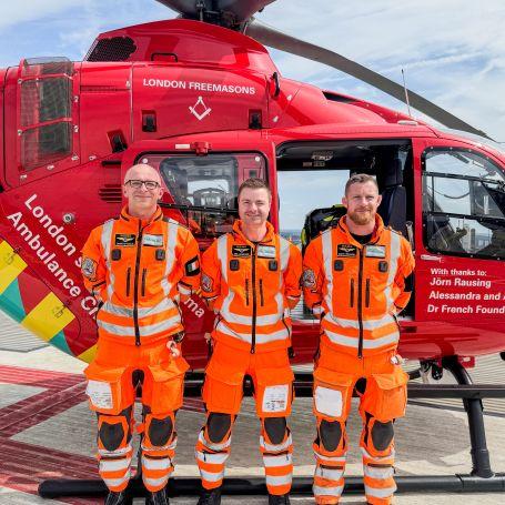 Three paramedics standing infront of helicopter